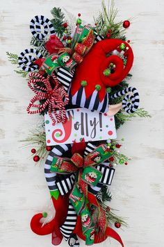 a christmas wreath with candy canes, holly and peppermint on it that says hello