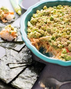 a bowl filled with food sitting on top of a table next to crackers and utensils