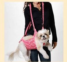 a woman holding a small white dog wearing a pink purse on it's back