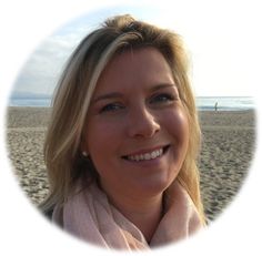 a woman with blonde hair and blue eyes smiles at the camera while standing on a beach