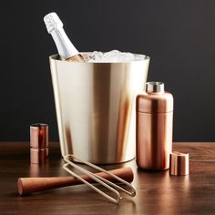 a bottle of champagne in an ice bucket next to some copper shakers and bottles