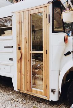 an old white bus with wood paneling and doors on the side, parked in gravel area