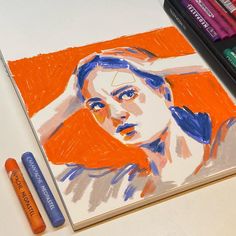 a drawing of a woman with orange hair and blue eyes is next to crayons