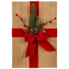 a christmas present wrapped in red ribbon with pine cones and berries on the top, tied to a wooden board