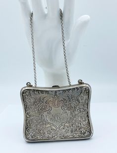 a silver purse sitting on top of a white mannequin