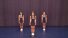 three cheerleaders standing in front of a purple curtain