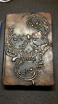 an intricately carved metal plaque next to a blue pen and pencil on a table