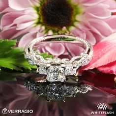 a diamond ring sitting on top of a pink flower next to a purple and white flower