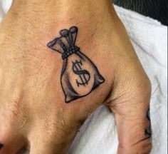 a person's hand with a tattoo on it and a money bag in the middle