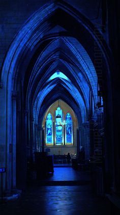 the inside of a church with blue light coming from it's stained glass windows