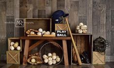 a wooden table topped with boxes filled with baseball equipment next to a wall covered in wood planks