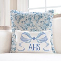 a blue and white pillow sitting on top of a couch next to a window with the word ahs printed on it