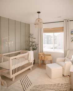 a baby's room with a crib, chair and ottoman