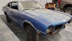 an old blue car sitting in a garage