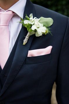 a man in a suit and pink tie with a boutonniere on his lapel