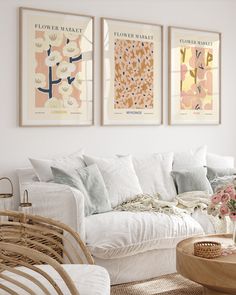 a living room filled with white furniture and paintings on the wall above it's couch