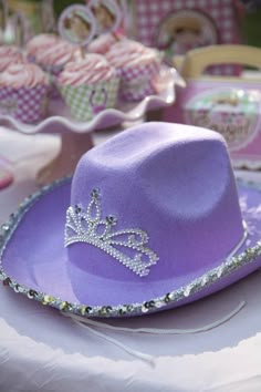 a purple hat sitting on top of a table next to cupcakes and muffins