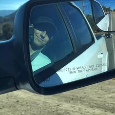 a side view mirror on the side of a car with a man in it's headphones