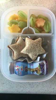 a plastic container filled with fruit, crackers and star shaped food next to a bottle of milk