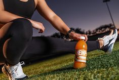 a woman is sitting on the grass with an empty bottle in front of her legs