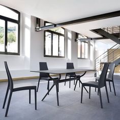 a dining room table and chairs in front of windows with stairs leading up to the second floor