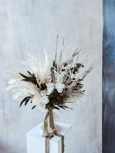 a bouquet of white flowers in a vase on a box with a ribbon tied around it