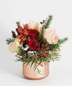 a vase filled with flowers and greenery on top of a table