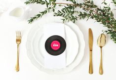 a place setting with an old vinyl record on the plate and gold cutlery next to it