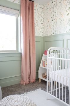 a baby's room with floral wallpaper and pink curtains