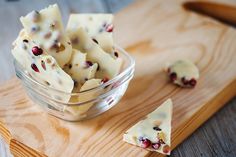 pieces of cheese and cranberries in a bowl on a cutting board