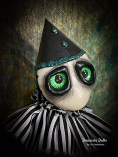 a creepy doll with green eyes wearing a black and white striped dress on top of it's head