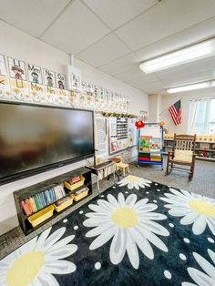 a classroom with an area rug, bookshelf and television