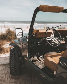 a jeep parked on the beach with its door open and steering wheel still in position