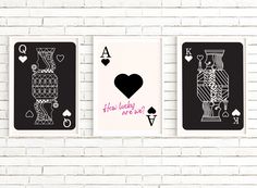 three playing cards on a white brick wall