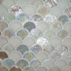 a close up view of a mosaic tile wall with silver and white circles on it