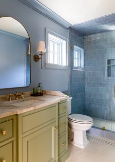 a bathroom with blue and green walls, gold fixtures and a white toilet in the corner