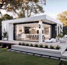 a modern house with an outdoor dining area in the back ground and grass around it