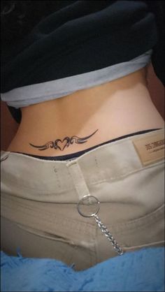 a woman's lower back tattoo with two birds on the side and a chain attached to it