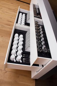 an open drawer with plates and silverware in it on a wood flooring surface