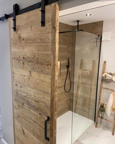 a bathroom with a sliding glass shower door and wooden paneling on the side wall