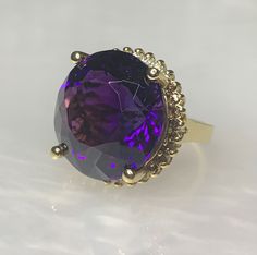 Amethyst Cocktail Ring, Round Amethyst Ring, Amethyst Diamond Ring, Amethyst Statement Ring, Vintage Amethyst Jewelry, Purple Gemstone Ring A one - of - a kind eye- catching super sized cocktail ring featuring a luminous round shaped 28.80 carat deep purple genuine amethyst surrounded by a halo of white and champagne fancy colored diamonds with a total weight of 0.75 carats. *Approximate stone measurements: 19.05 mm all around *Approximate ring weight: 15.52 grams *Ring size: 5 3/4 *Complimentar Dainty Earrings Studs, Antique Emerald Ring, Amethyst Cocktail Ring, Vintage Sapphire Ring, Emerald Ring Vintage, Jewelry Purple, Vintage Cocktail Ring, Amethyst And Diamond Ring, Vintage Sapphire