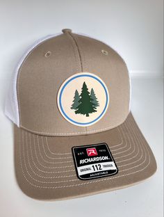 a brown and white trucker hat with a pine tree patch on the front of it