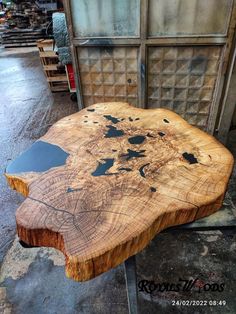 a table made out of wood with black paint on the top and bottom, sitting in front of a window