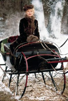 a woman sitting on top of a sleigh in the snow