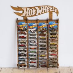 a wooden sign that says hot wheels on the side of a wall with toy cars in it