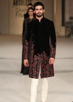 a man in a black and red outfit on the runway