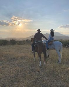 two people are riding horses in an open field