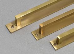 three brass metal handles on a white surface