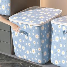 two blue storage boxes with white daisies on them, one is open and the other is closed