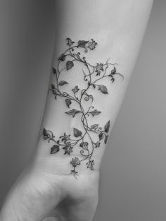 a black and white photo of a wrist tattoo with vines on the left side of the arm